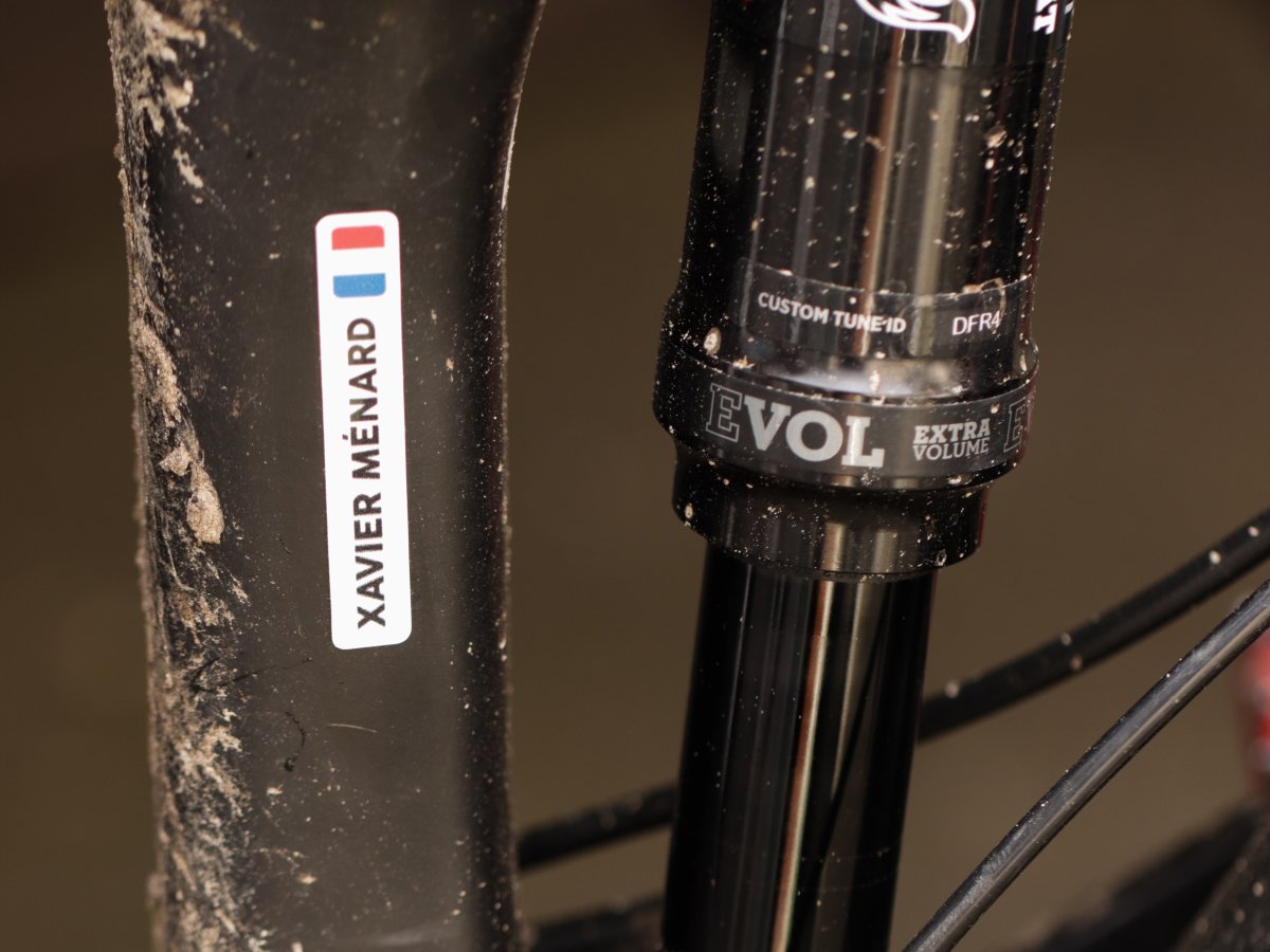 White name sticker with a French flag on the seat tube of a muddy mountain bike