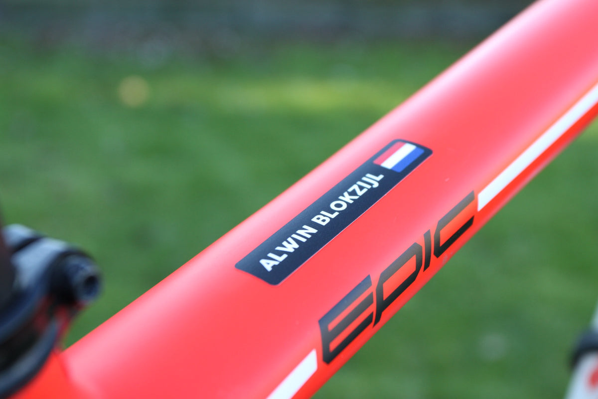 Black name sticker with a Dutch flag on the red top tube of a mountain bike