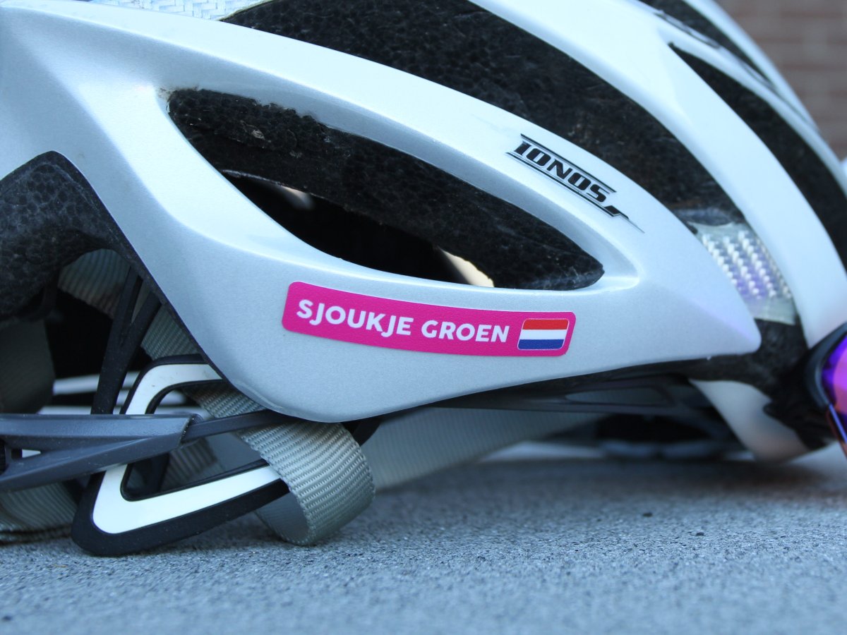 Pink name sticker with a Dutch flag on a white bike helmet