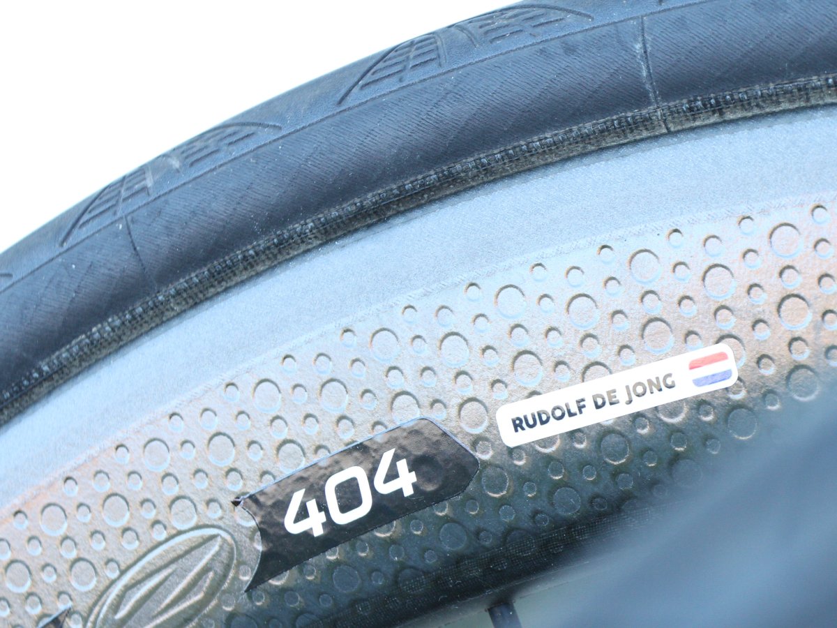 White name sticker with a Dutch flag on a carbon rim